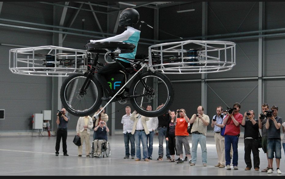 Journalists attend a presentation of a flying bicycle, carrying a dummy, at Letnany's fair hall 