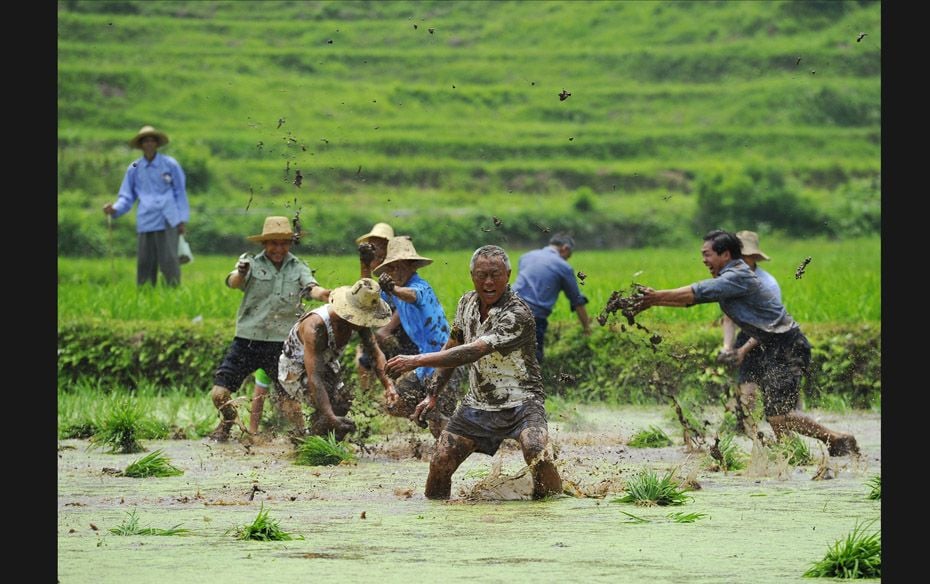 People throw mud onto each other at a crop field during the Hucang Festival at Zhangjiajie, Hunan pr