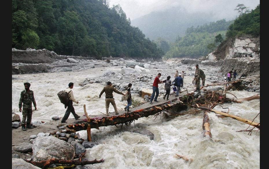 Indian army personnel help stranded people cross a flooded river after heavy rains in the Himalayan 