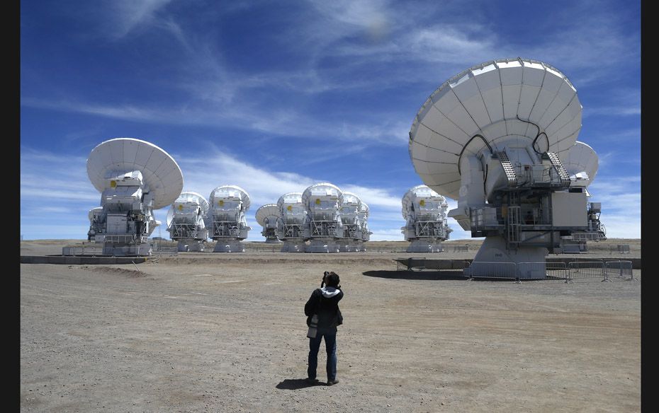 A member of the media takes pictures of the parabolic antennas of the ALMA (Atacama Large Millimetre