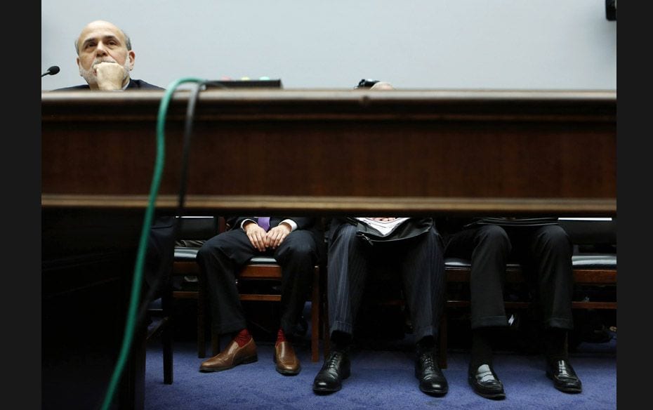 Chairman of the US Federal Reserve Ben Bernanke listens with his staff while he testifies before the