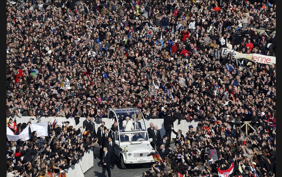 Pope Benedict XVI waves from his Popemobile as he rides through a packed Saint Peter's Square at