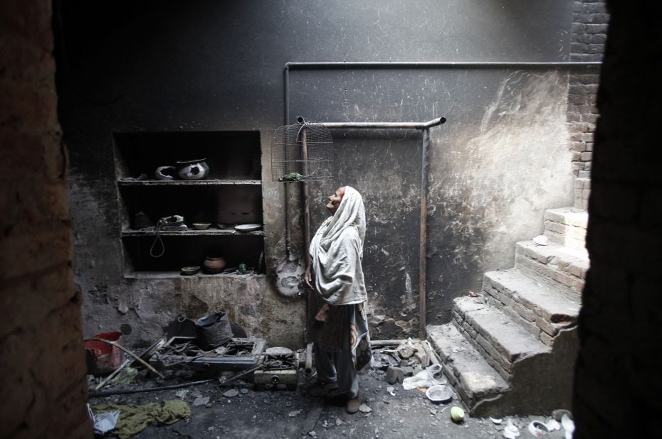 Azra, 68, looks at her dead pet bird in a cage at her home, which was burnt by a mob two days earlie