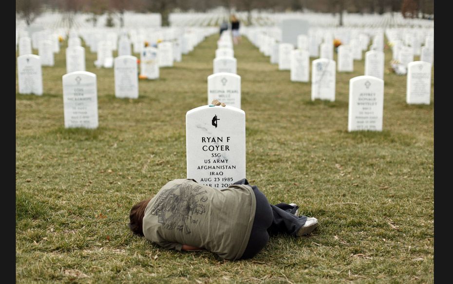 Lesleigh Coyer, 25, of Saginaw, Michigan, lies down in front of the grave of her brother, Ryan Coyer