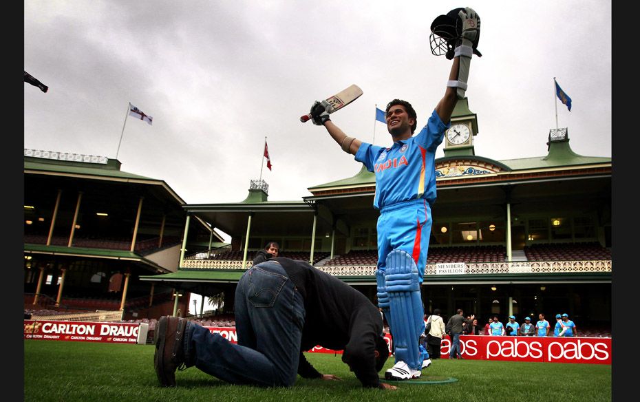 An Indian cricket supporter kneels in front of a wax figure of Indian cricketer Sachin Tendulkar dur