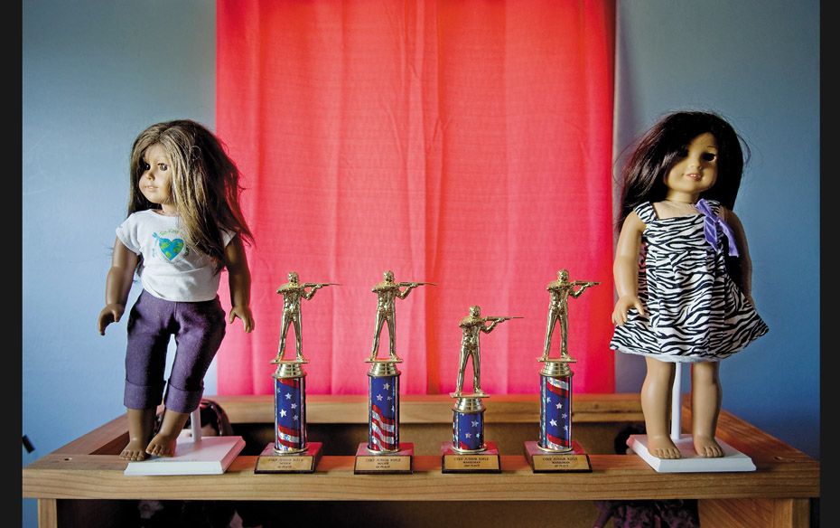 Trophies won by a 7-year-old girl in shooting competitions adorn a shelf in her room                