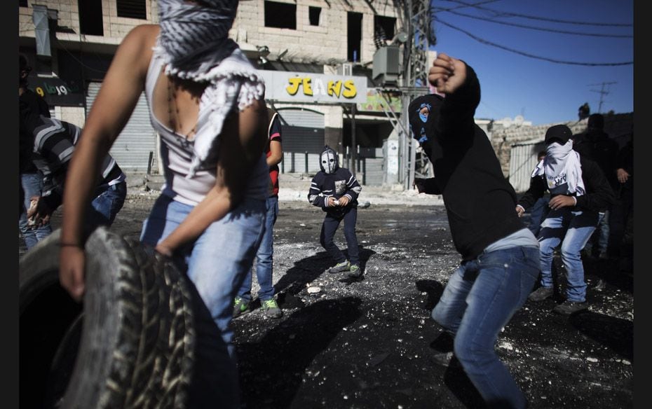 Palestinian youths throw stones towards the Israeli border police during clashes at a checkpoint bet