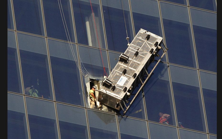 Workers look at a broken scaffolding on which two window-washers were left stranded on the 69th floo