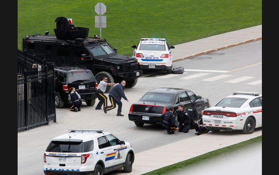 Police officers take cover near Parliament Hill on October 22 after a masked gunman killed a soldier