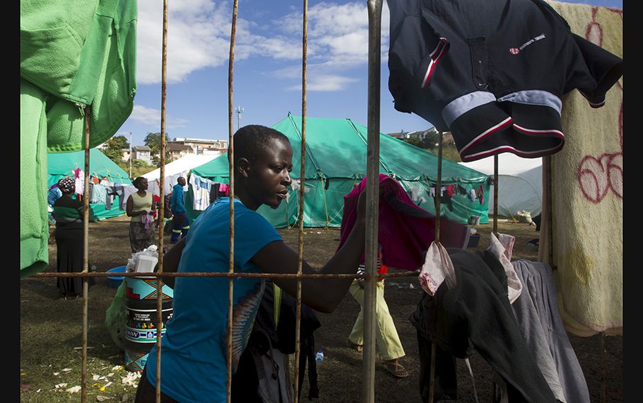 A foreign woman from Zimbabwe fetches dry clothes from the fence at a camp set up to house those aff