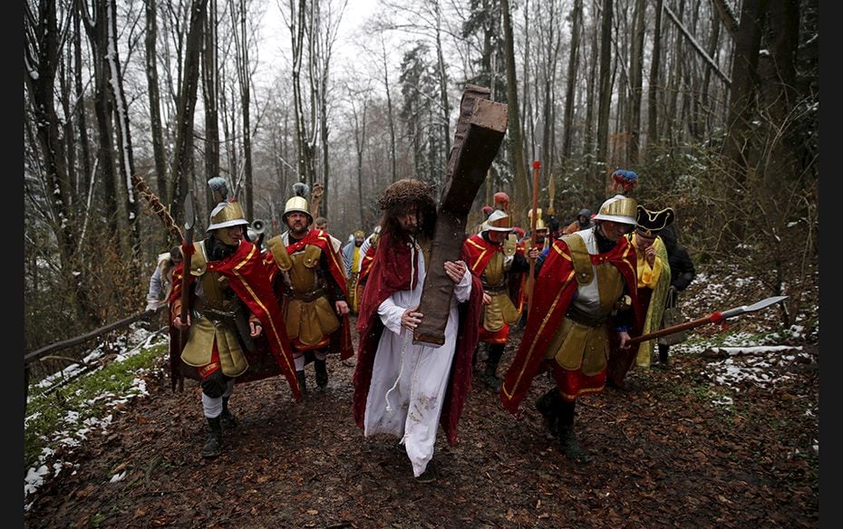 An actor playing Jesus Christ carries a cross in a procession of the Way of the Cross on Good Friday