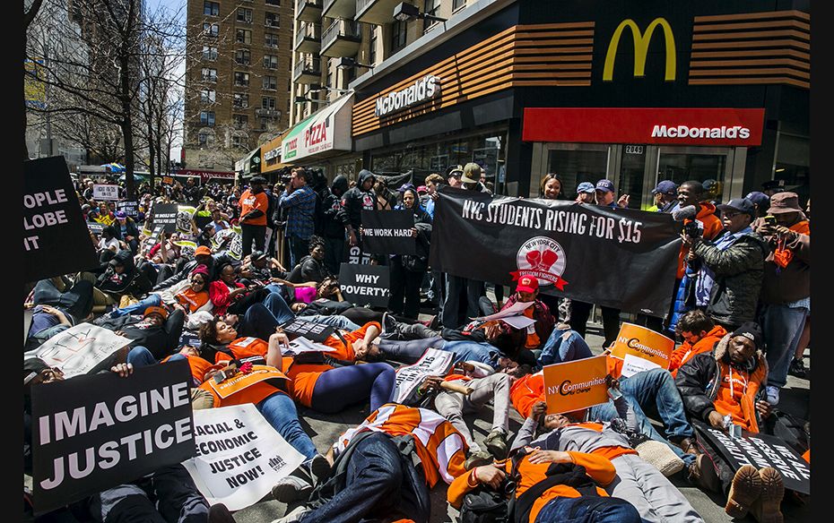 Protesters participate in a "die in" in front of a McDonald's restaurant during demons