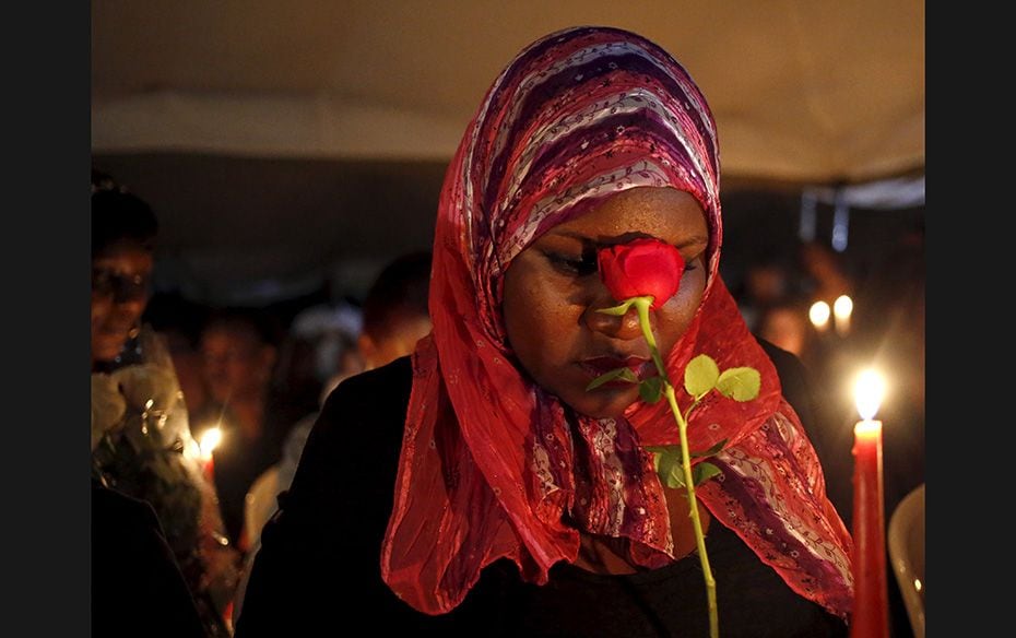 A woman holds a rose as she prays during a memorial vigil following an attack by gunmen at the Garis