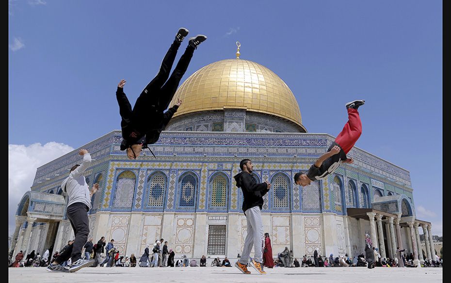 The Dome of the Rock is seen in the background as Palestinian youths practice their parkour skills d