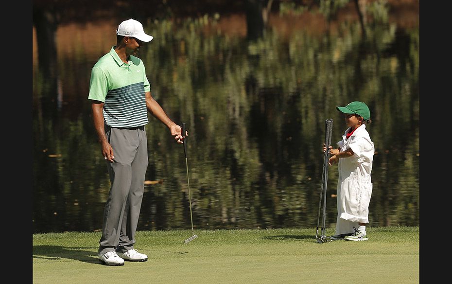 U.S. golfer Tiger Woods' son Charlie caddies for his father on the ninth green during the par 3 