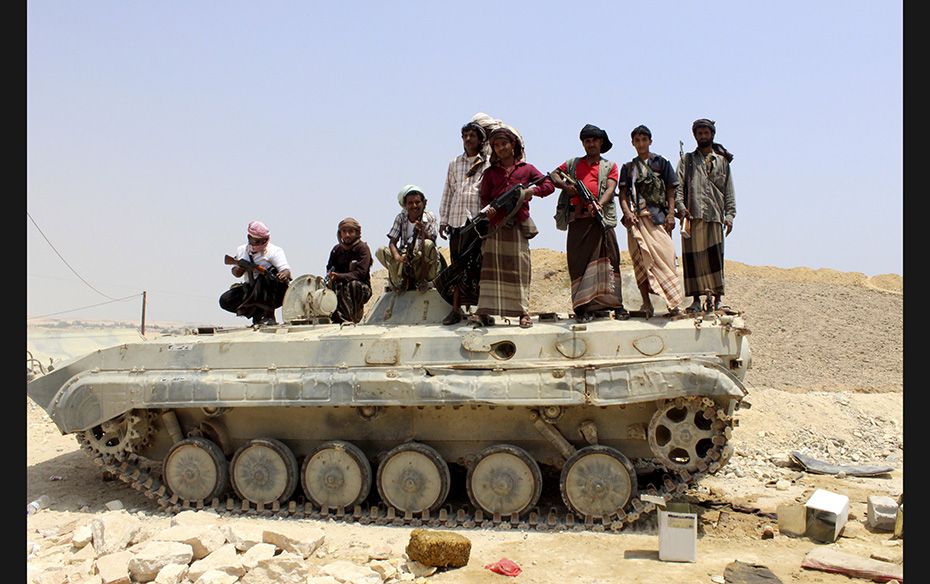 Tribesmen stand on a military vehicle they took from an army base in the Ash Shihr city of Yemen'