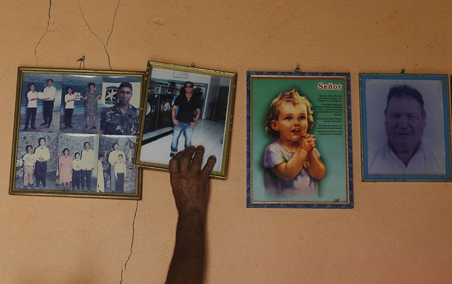 Benjamin Aceituno reaches for a photo frame of his son, Juan Carlos Aceituno, who disappeared during