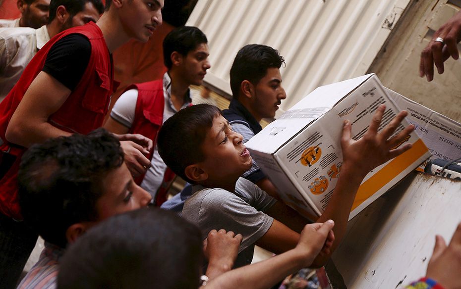 Boys help members of the Syrian Arab Red Crescent to load parcels of medical and humanitarian aid in