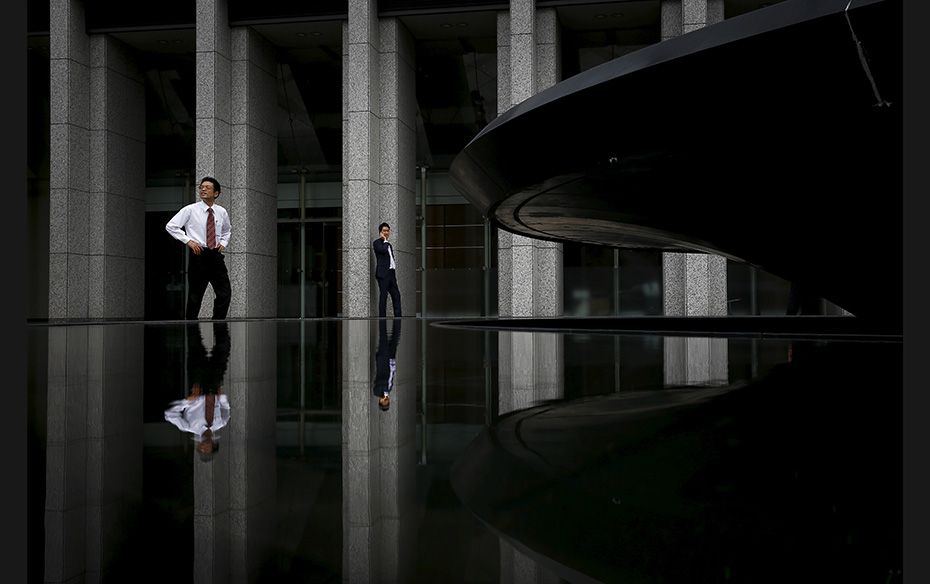 Businessmen are reflected in a fountain outside an office building in Tokyo, Japan, on August 14. Be