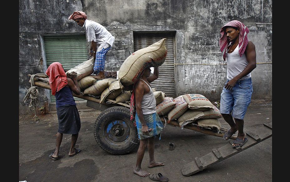 Labourers unload sacks of rice from a handcart at a wholesale market in Kolkata on December 14. Indi