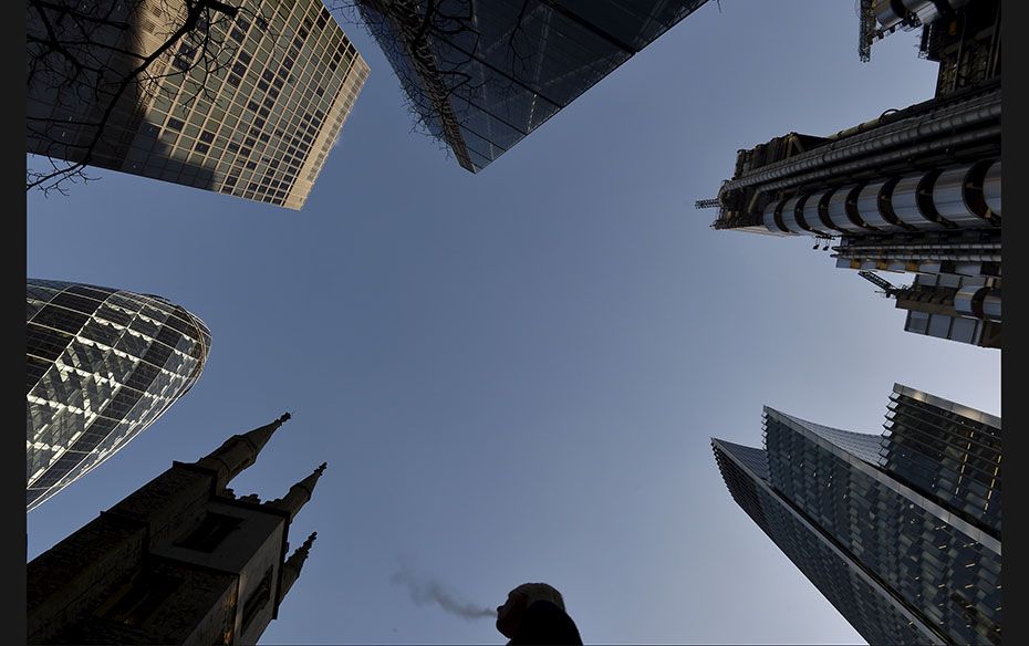 A city worker walks through the City of London with St Andrew Undershaft church surrounded by busine