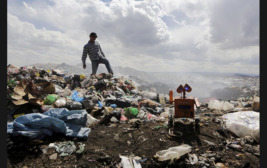 Bolivian student Esteban Quispe, 17, walks on a rubbish dump as a replica of his Wall-E robot is see