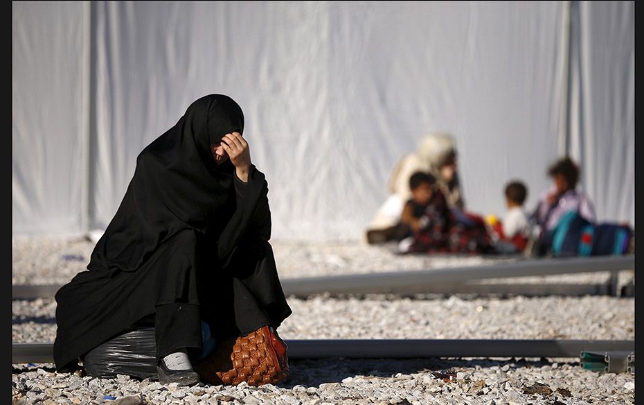 A migrant waits in front of a refugee centre after crossing the border from Greece to Macedonia on N