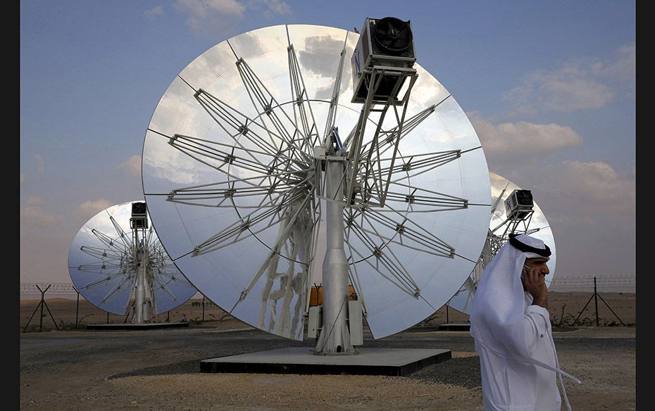 A man speaks on the phone as he walks past solar panels at the Mohammed bin Rashid Al Maktoum Solar 