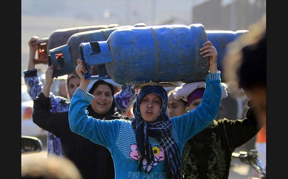 Women carry gas cylinders at a distribution point in Cairo on January 19, 2015. Egypt is going throu