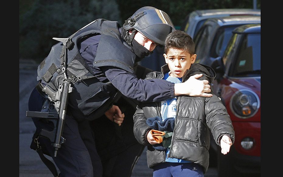 A French police officer speaks to a child as he secures an access to a school at the Castellane hous