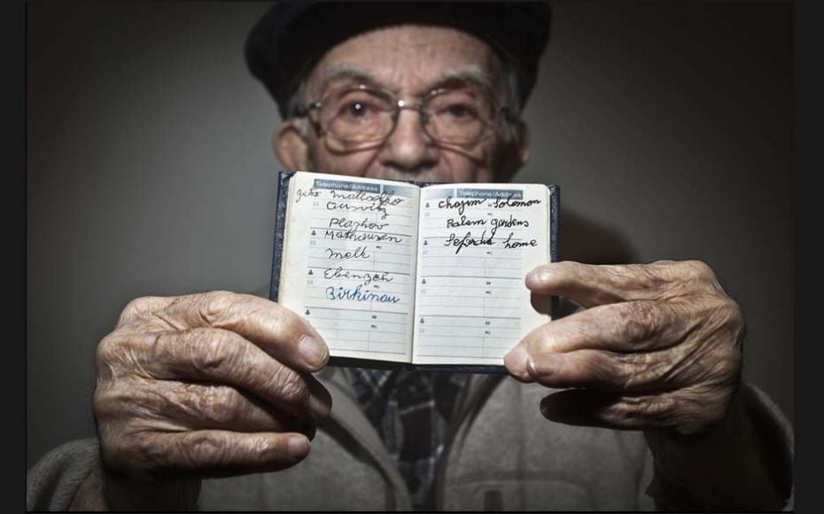 Holocaust survivor Hy Abrams, 90, poses for a portrait with a book that he carries with him every da