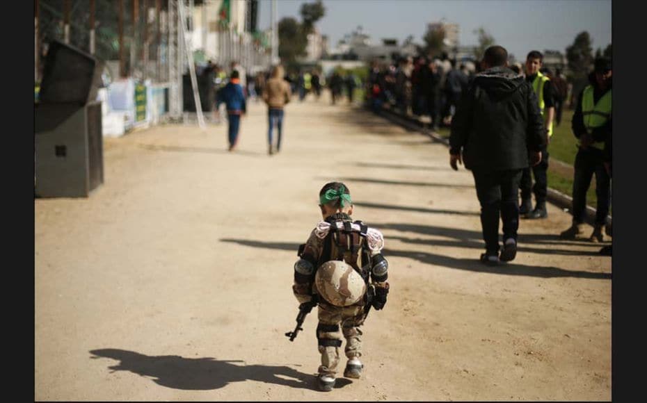 A Palestinian boy wearing a military costume arrives at a military-style graduation ceremony for Pal