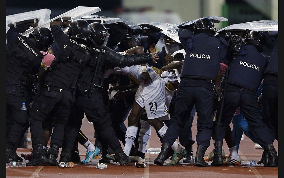 Riot police shield Ghana's John Boye (21) and team mates from objects thrown by Equatorial Guine