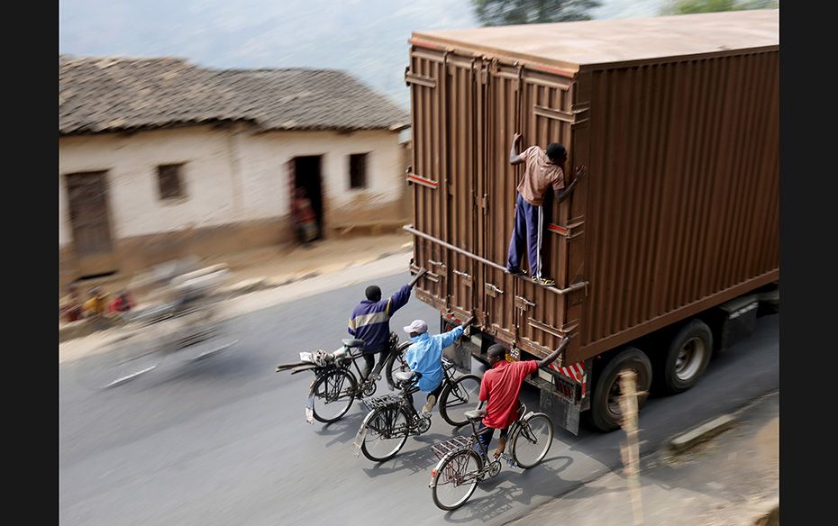 Cyclists in Burundi hang on to the back of a truck outside the capital Bujumbura on July 19, as the 