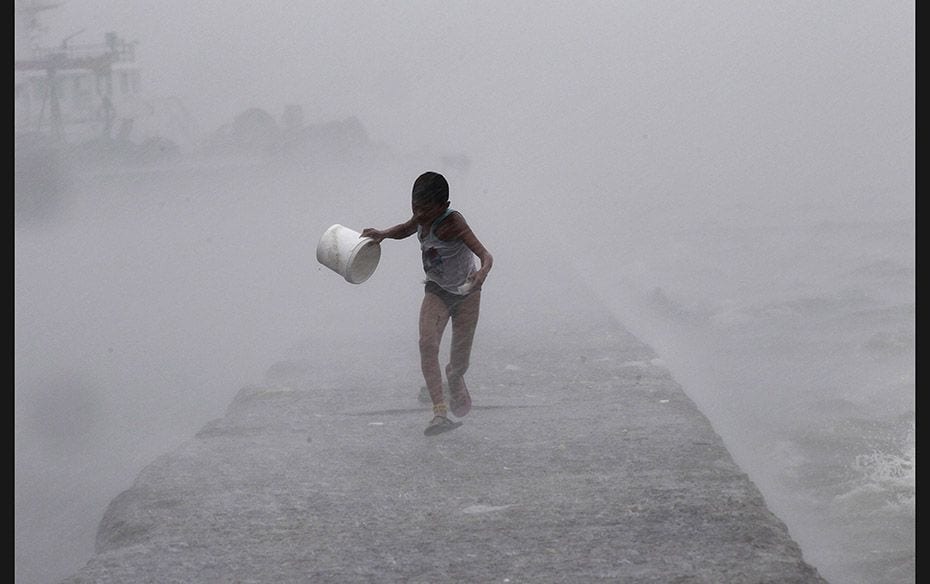 A boy runs as heavy rains and high waves brought about by typhoon Linfa, locally named Egay, crash a