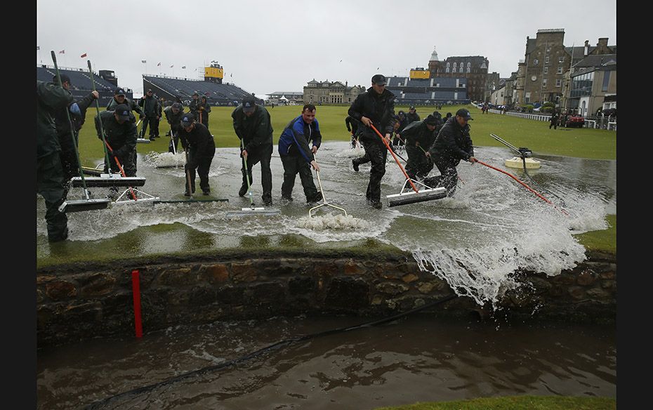 Groundstaff remove water from the course after torrential rain forced play to be suspended during th