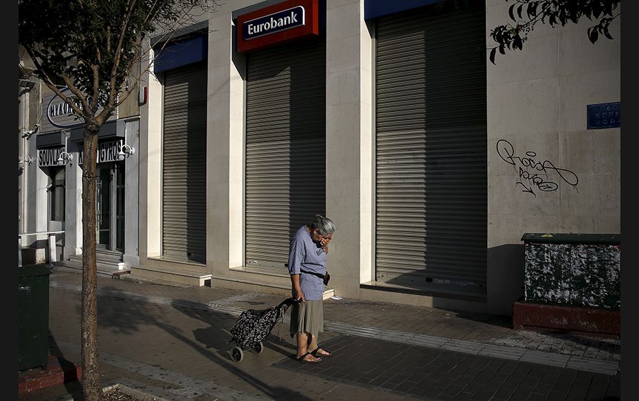 A woman pulls a shopping cart outside a closed Eurobank branch in Athens, Greece, on June 29. Greece