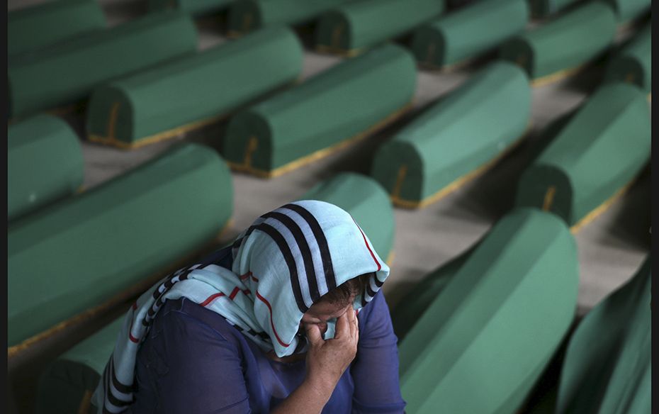 A woman cries near the coffin of her relative who was among the 136 newly identified victims of the 