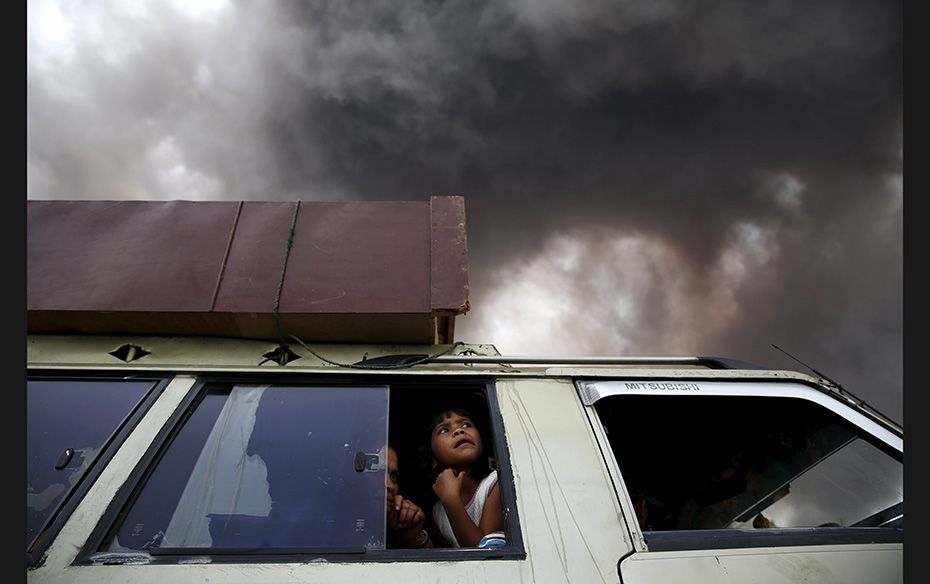 A family sits inside a car as ash spews from Mount Sinabung volcano during an eruption at Tiga Seran