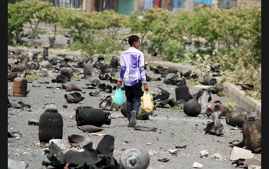 A boy walks on a street littered with cooking gas cylinders after a fire and explosions destroyed a 