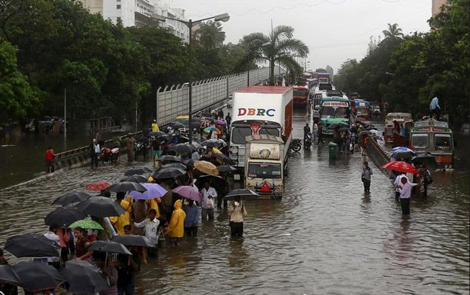 People walk through flooded roads as vehicles are seen caught in bumper-to-bumper traffic after heav