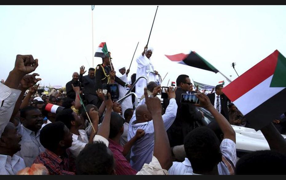 Sudanese President Omar al-Bashir (C) waves to his supporters at the airport in the capital city of 