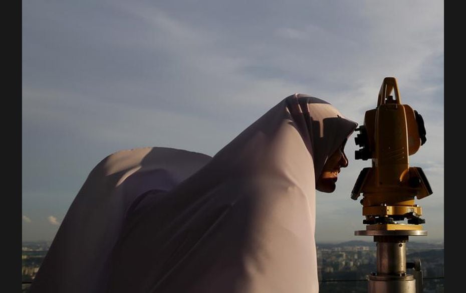 A Muslim woman uses a theodolite to perform ‘rukyah’, the sighting of the new moon which