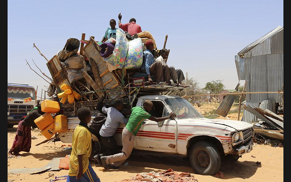 Displaced Somali families help push a pick-up truck carrying personal belongings from a camp which w