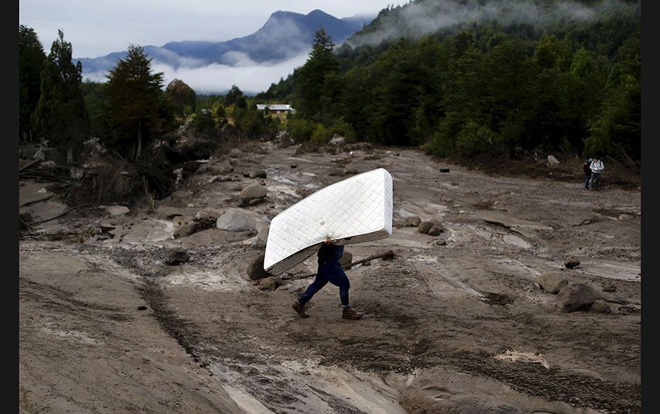 A resident carries a mattress through an area damaged by lahar (hot or cold mixture of water and roc