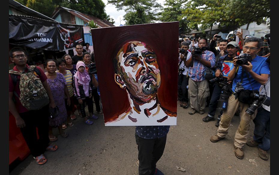 A man carries a self-portrait painted by Australian death row prisoner Myuran Sukumaran as he leaves