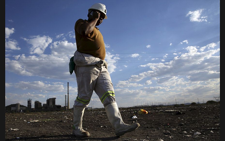 A mine worker speaks on his phone as he returns from the Lonmin mine at the end of his shift, outsid