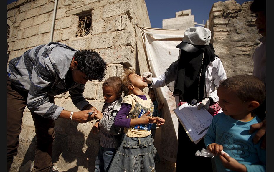 Health workers administer polio vaccine for children during a house-to-house vaccination campaign in