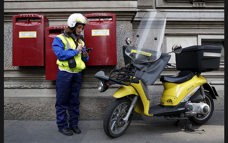 A postwoman checks her phone in front of the headquarters of Poste Italiane in Milan on October 22. 