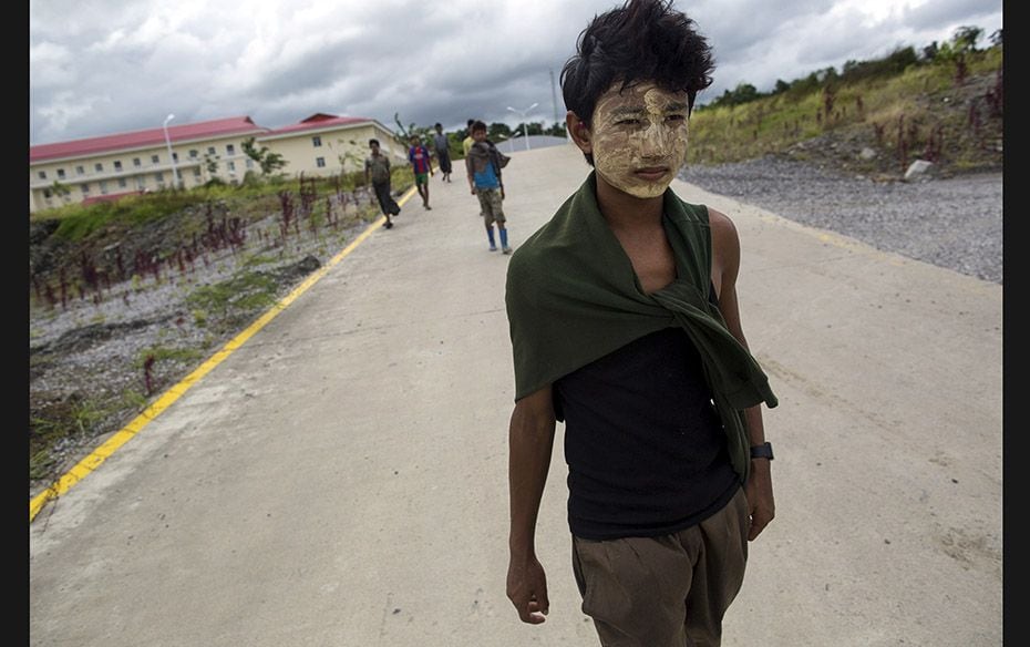 Workers walk on a road as China's oil pipeline project is seen in the background in Myanmar&rsqu